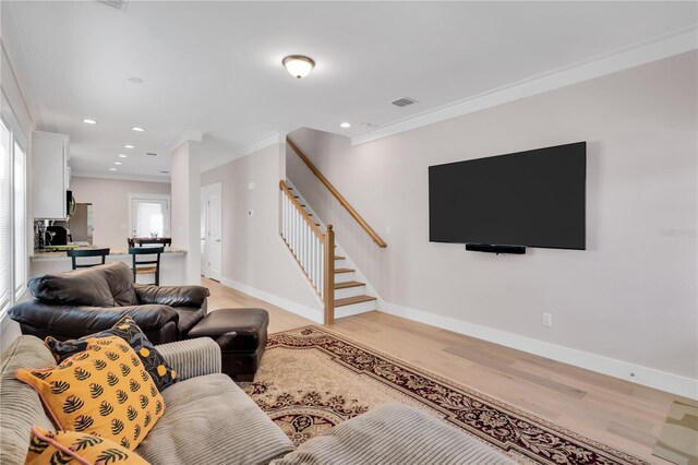 living room featuring crown molding and light hardwood / wood-style flooring