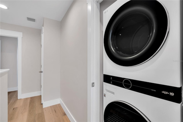 washroom featuring light hardwood / wood-style floors and stacked washer / dryer