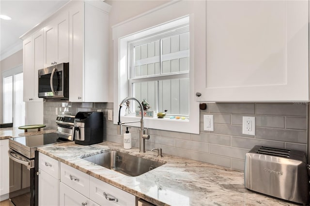 kitchen with light stone countertops, stainless steel appliances, decorative backsplash, white cabinetry, and sink