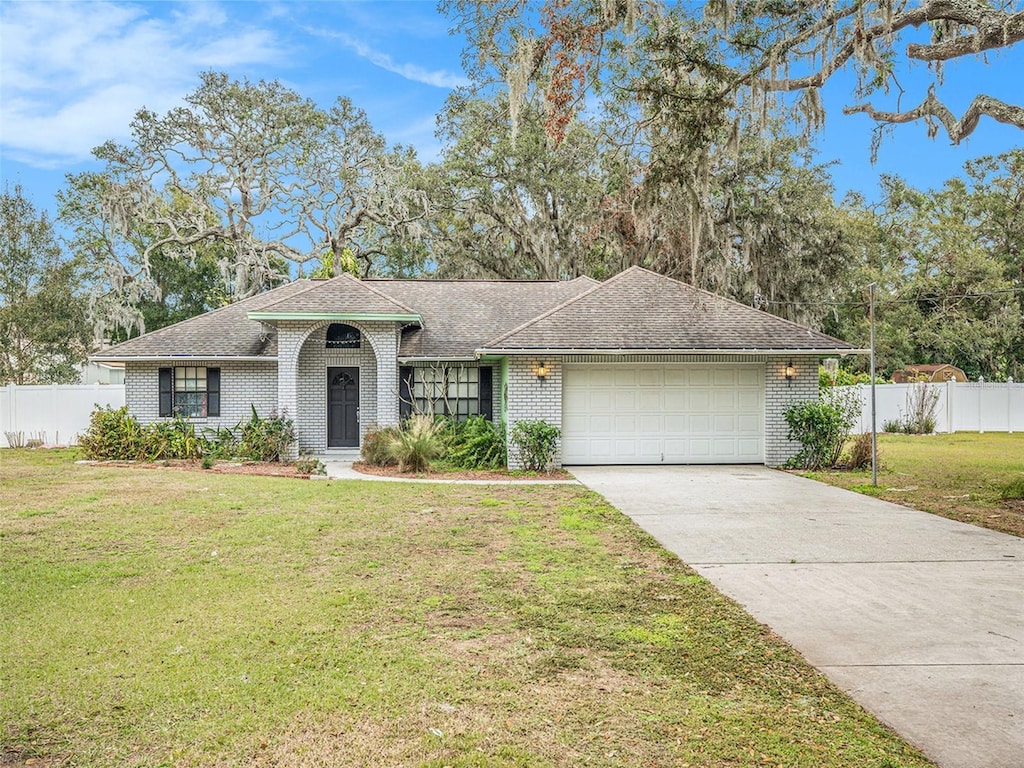 ranch-style house featuring a garage and a front lawn