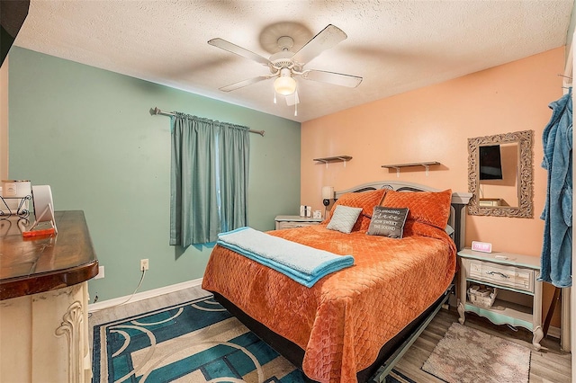 bedroom with ceiling fan, hardwood / wood-style floors, and a textured ceiling