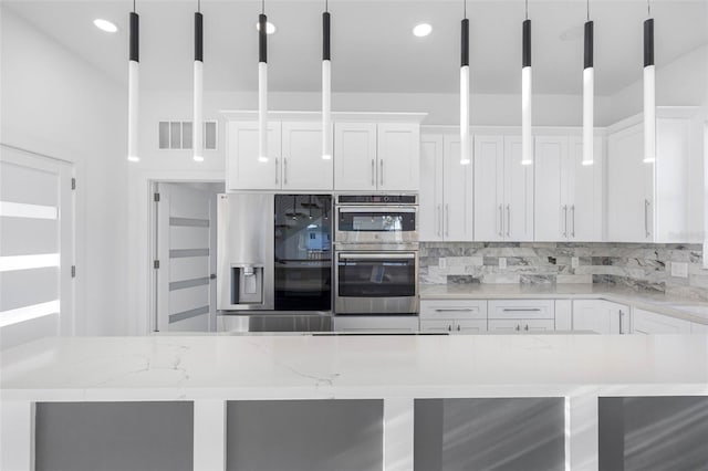 kitchen featuring hanging light fixtures, white cabinets, light stone countertops, and stainless steel appliances