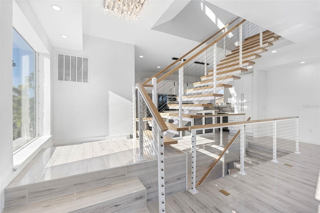 stairs featuring hardwood / wood-style floors and a chandelier