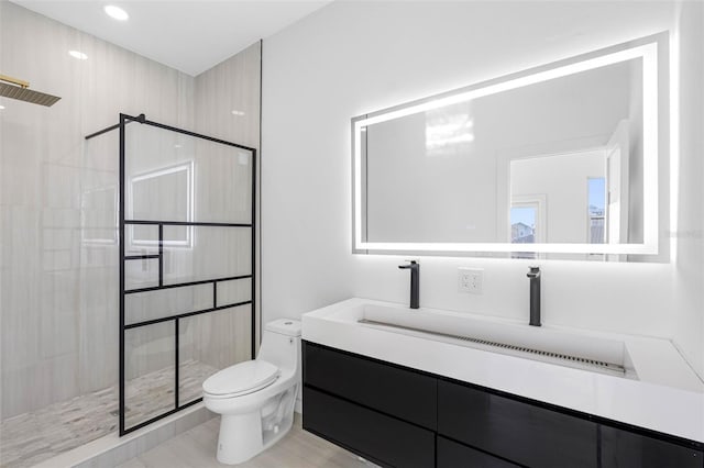 bathroom with toilet, vanity, and a tile shower