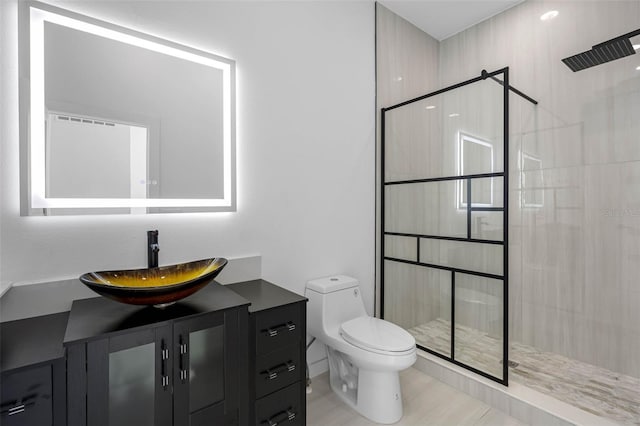 bathroom with toilet, tiled shower, and vanity