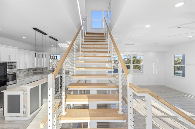 stairs with wood-type flooring and a notable chandelier