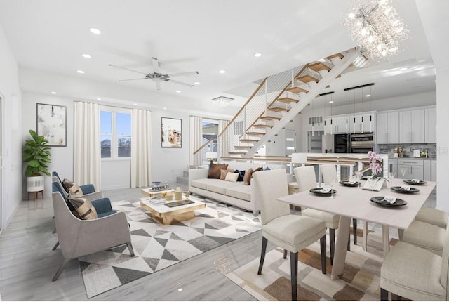 living room featuring ceiling fan with notable chandelier and light hardwood / wood-style floors