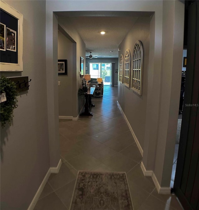 hallway with a textured ceiling and tile patterned floors