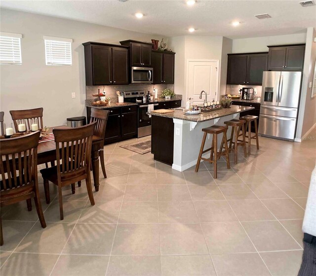 kitchen featuring appliances with stainless steel finishes, an island with sink, and light tile patterned floors