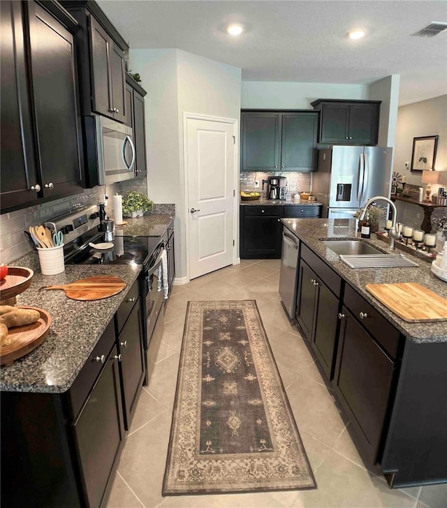 kitchen featuring appliances with stainless steel finishes, light tile patterned flooring, backsplash, and sink