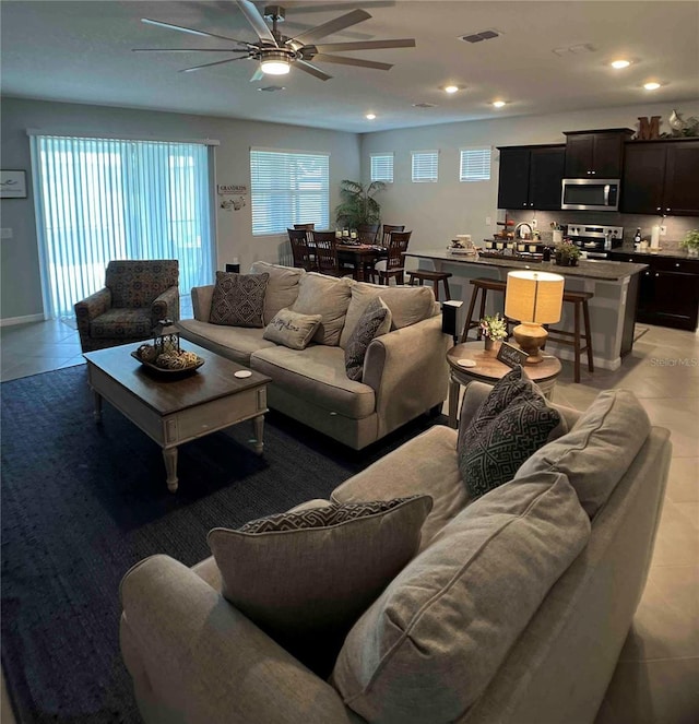 living room with sink, ceiling fan, and light tile patterned floors