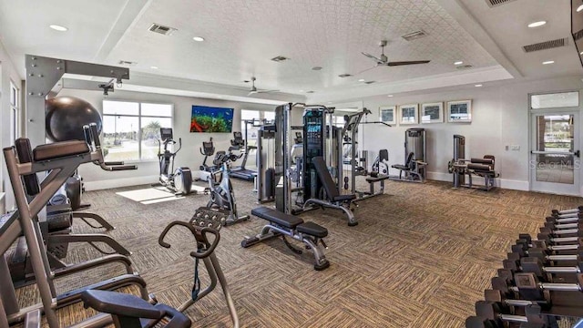 gym with a raised ceiling, carpet floors, and ceiling fan