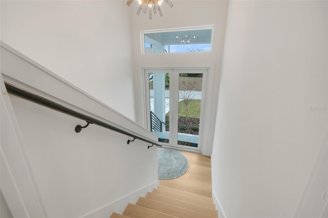 stairway with hardwood / wood-style floors and a notable chandelier