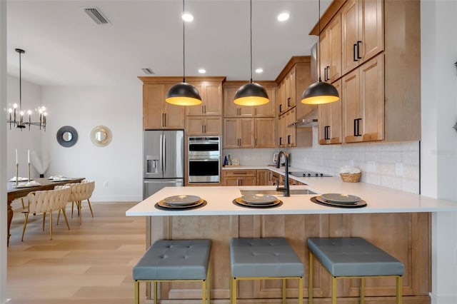 kitchen with tasteful backsplash, a breakfast bar, kitchen peninsula, and appliances with stainless steel finishes