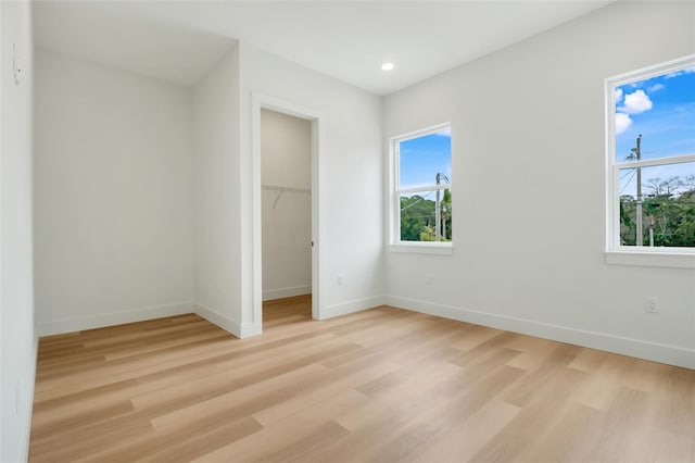 unfurnished bedroom featuring a walk in closet, light wood-type flooring, and a closet