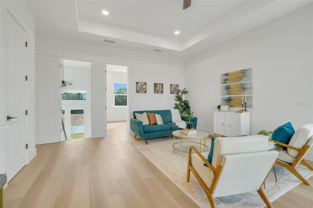 living room with a tray ceiling and light hardwood / wood-style flooring