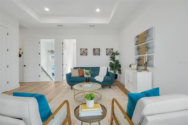 living room with hardwood / wood-style flooring and a raised ceiling