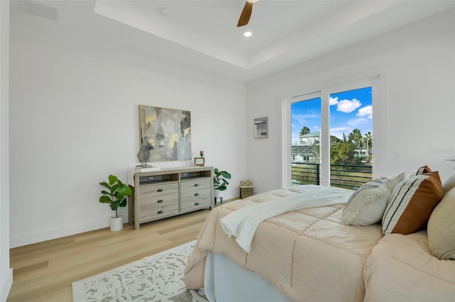 bedroom featuring a raised ceiling, access to outside, ceiling fan, and light hardwood / wood-style flooring