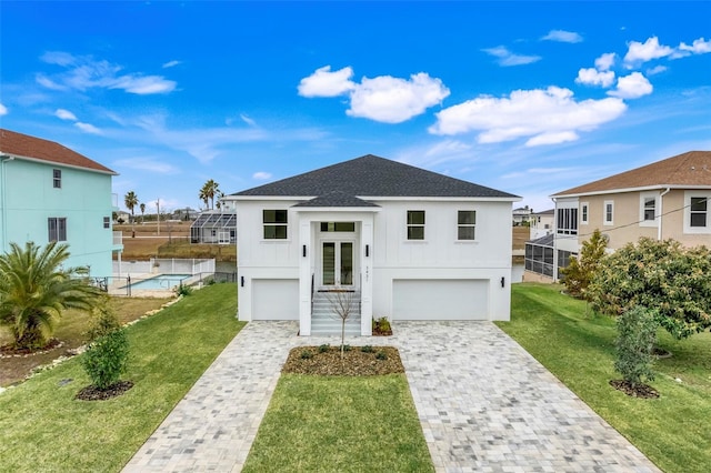 view of front of property with stucco siding, a shingled roof, decorative driveway, a front yard, and an attached garage