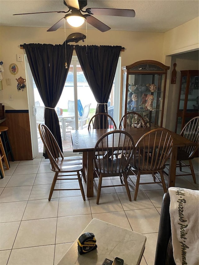 tiled dining room with ceiling fan and wooden walls