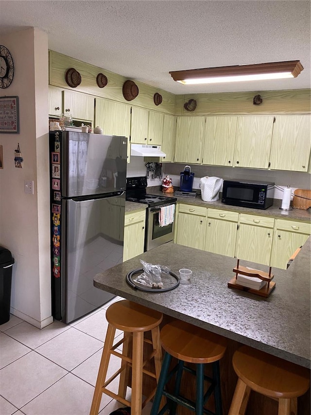 kitchen featuring stainless steel appliances, a textured ceiling, light tile patterned flooring, kitchen peninsula, and a breakfast bar area