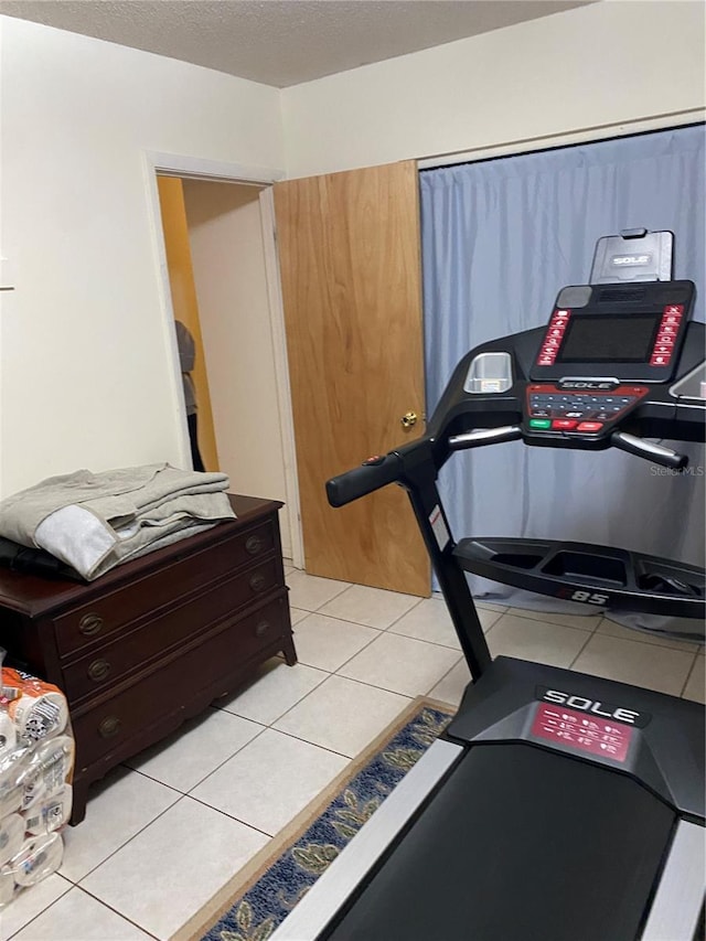 exercise area featuring a textured ceiling and light tile patterned floors