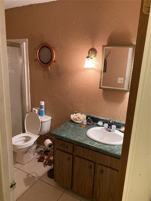 bathroom featuring a shower with door, tile patterned flooring, vanity, and toilet