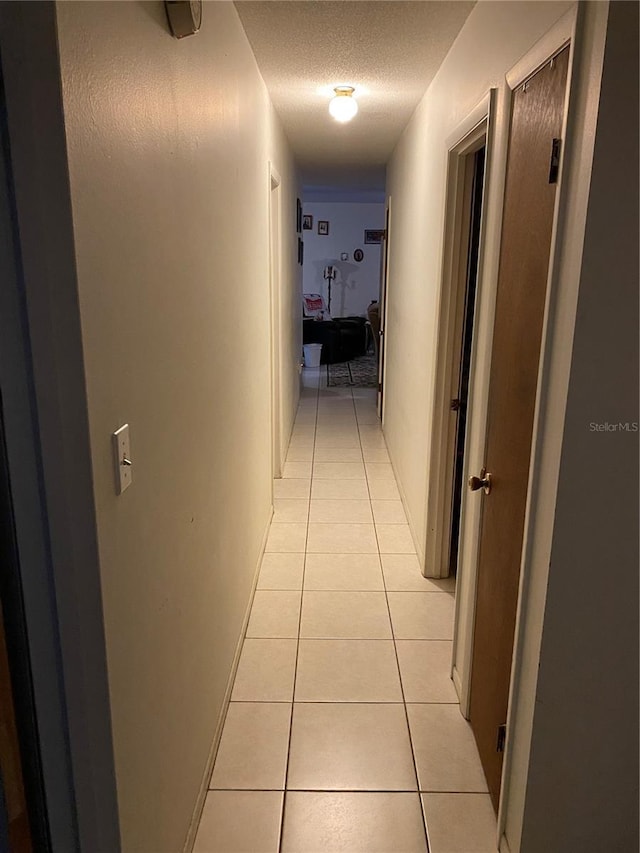 hall with light tile patterned flooring and a textured ceiling