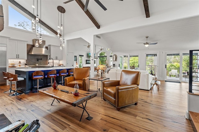 living room with high vaulted ceiling, light hardwood / wood-style flooring, and beam ceiling