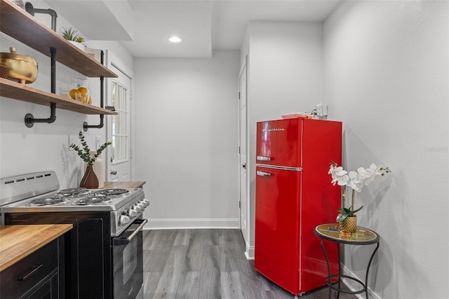 kitchen featuring stainless steel range oven, refrigerator, hardwood / wood-style floors, and wooden counters