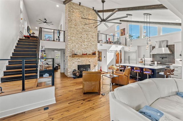 living room with ceiling fan, a healthy amount of sunlight, beamed ceiling, and a fireplace