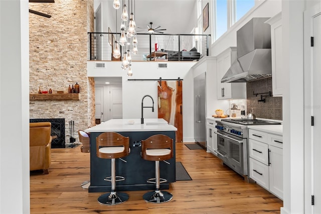 kitchen with tasteful backsplash, range with two ovens, a towering ceiling, pendant lighting, and wall chimney exhaust hood