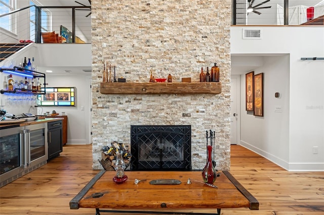 living room with ceiling fan, wood-type flooring, a fireplace, and a high ceiling