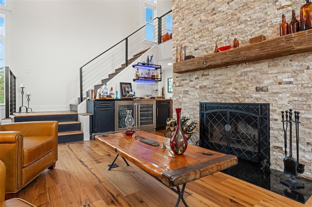 living room featuring bar, a fireplace, wine cooler, and light hardwood / wood-style flooring