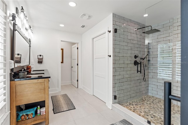 bathroom with tiled shower, vanity, and tile patterned flooring