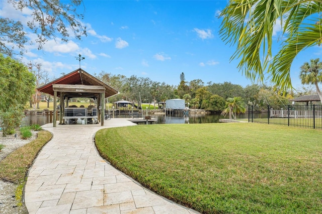 view of property's community featuring a water view, a boat dock, and a lawn