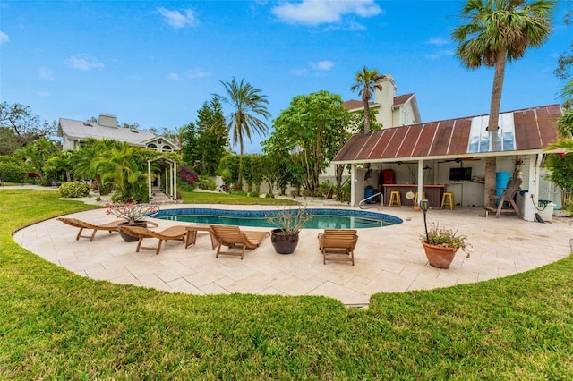 view of swimming pool featuring a lawn, an outdoor bar, a patio, and area for grilling