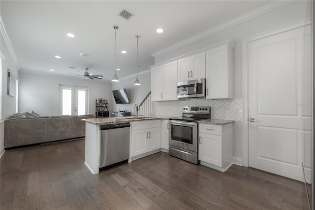 kitchen with white cabinets, kitchen peninsula, hanging light fixtures, light stone countertops, and appliances with stainless steel finishes