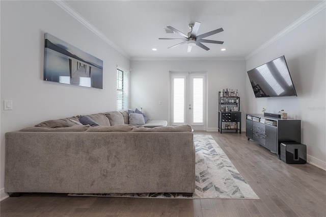 living room featuring hardwood / wood-style flooring, ceiling fan, and crown molding