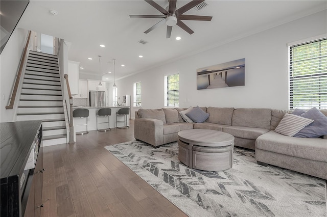 living room with dark wood-type flooring, ceiling fan, and ornamental molding