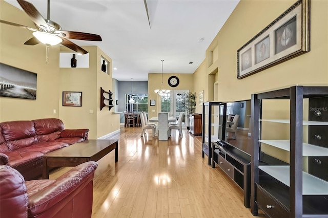 living room with light hardwood / wood-style floors and ceiling fan with notable chandelier