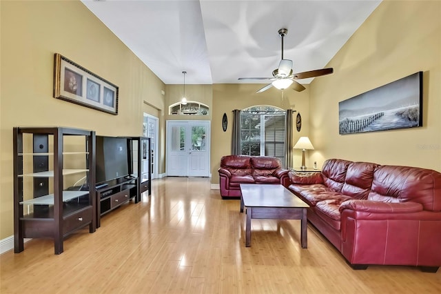 living room with light hardwood / wood-style floors, ceiling fan, and vaulted ceiling