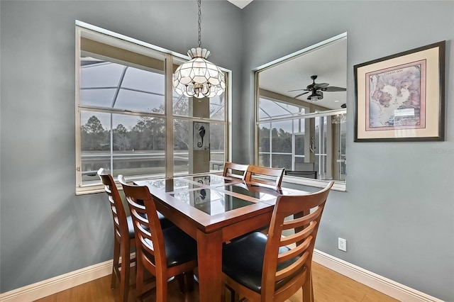 dining area with ceiling fan with notable chandelier and hardwood / wood-style flooring