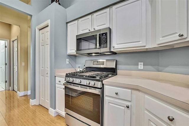 kitchen with appliances with stainless steel finishes, light hardwood / wood-style floors, and white cabinetry