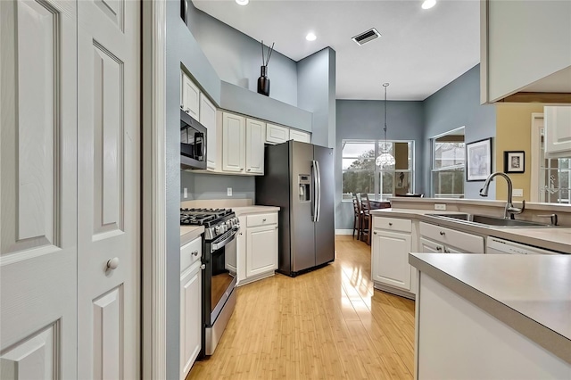 kitchen with sink, decorative light fixtures, white cabinetry, and appliances with stainless steel finishes