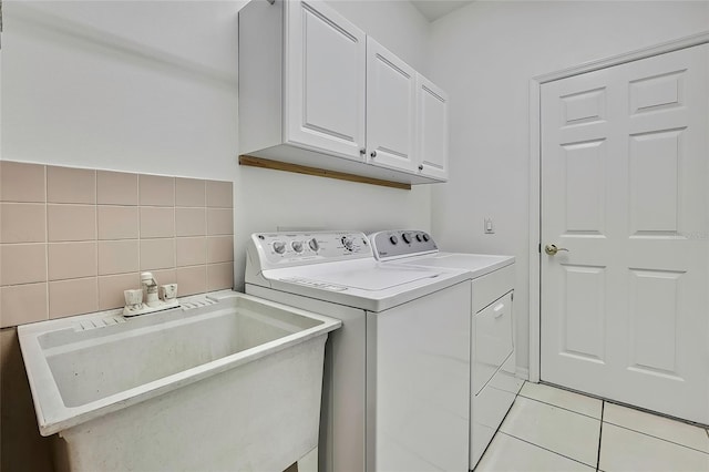 laundry room featuring sink, light tile patterned floors, separate washer and dryer, and cabinets