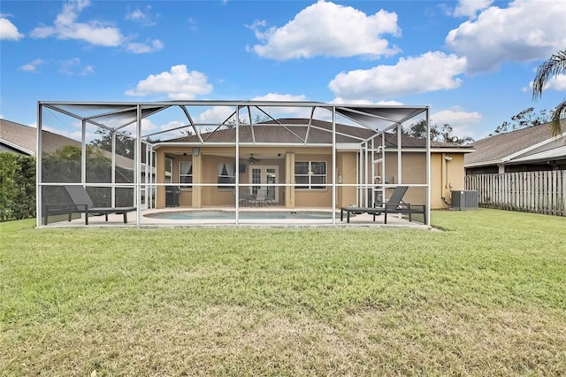 back of house featuring a lawn, ceiling fan, glass enclosure, cooling unit, and a patio area