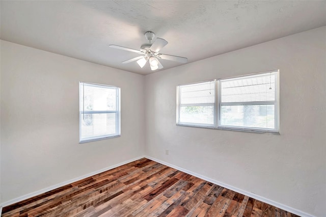 spare room with ceiling fan, dark wood-type flooring, and a wealth of natural light