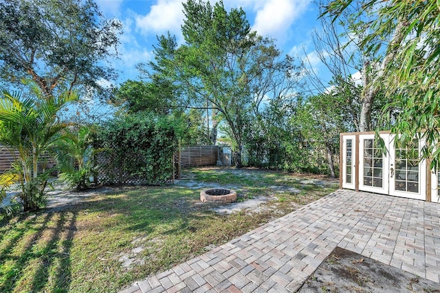 view of yard featuring an outdoor fire pit, an outbuilding, french doors, and a patio