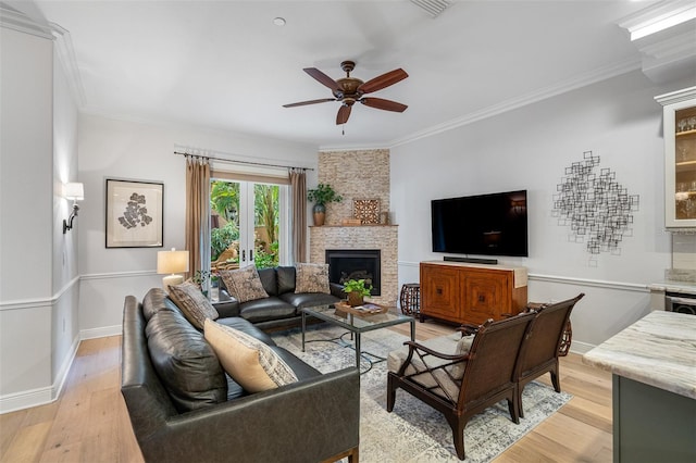 living room with french doors, light wood-type flooring, crown molding, a fireplace, and ceiling fan